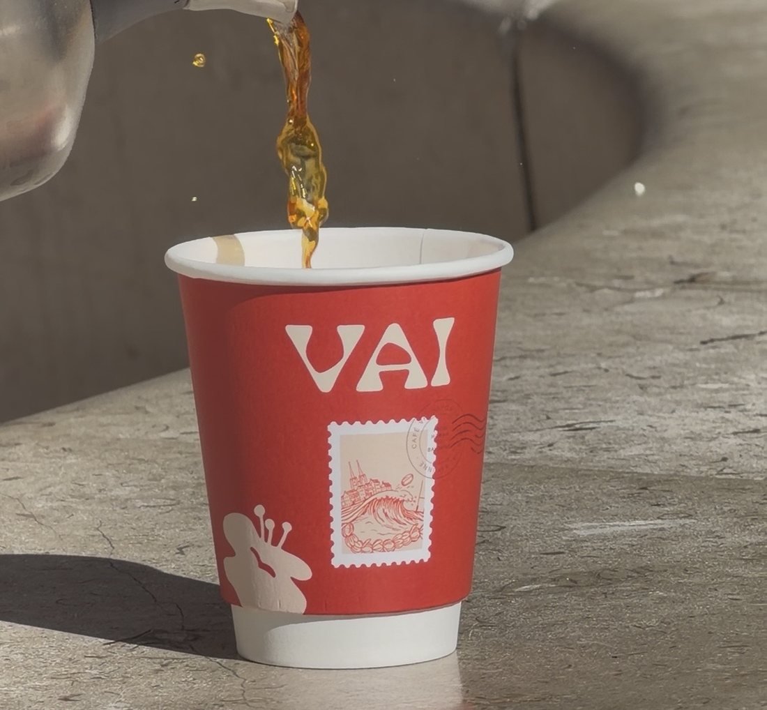 Coffee being poured into a red custom-printed paper cup